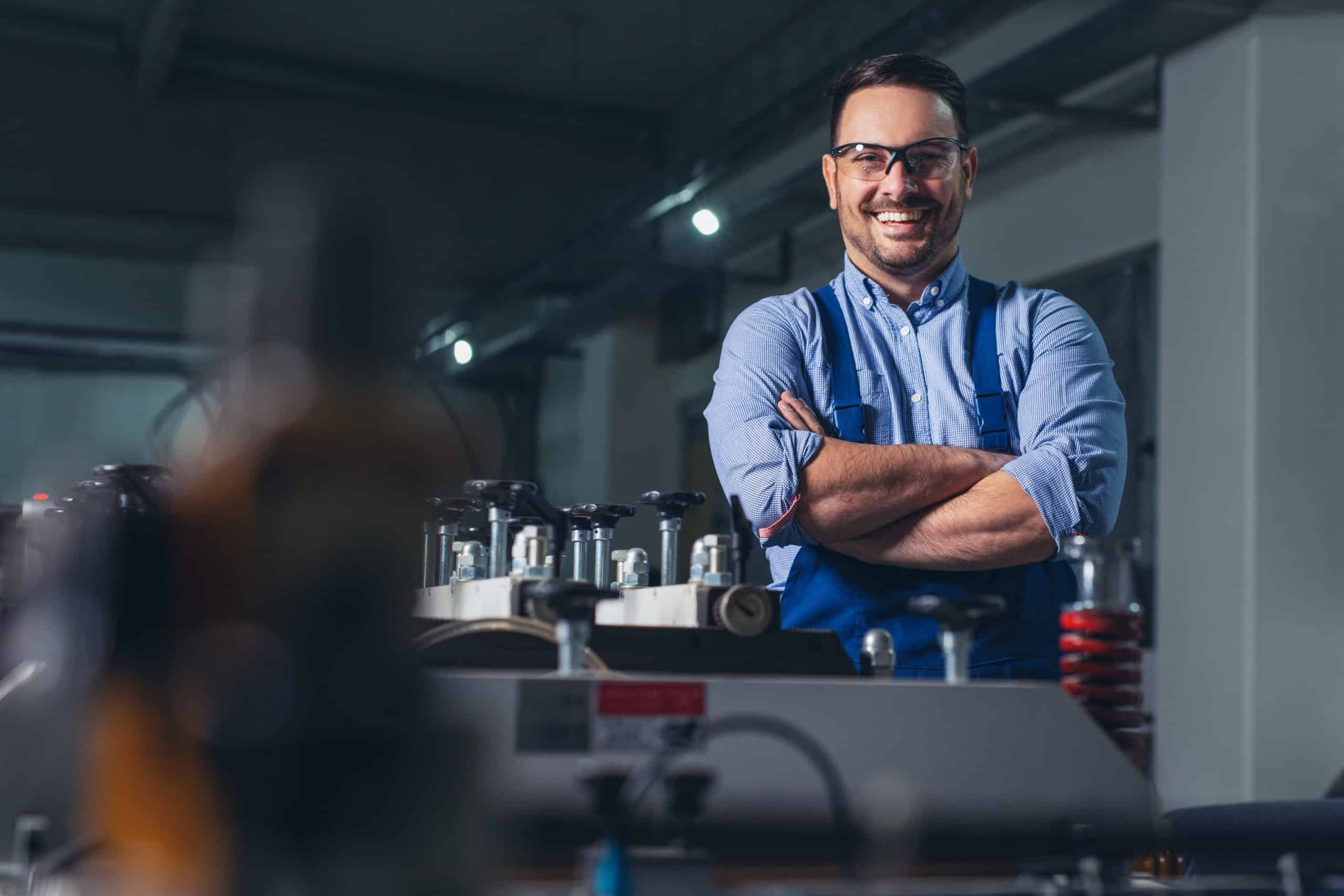 Fröhlicher Fabrikarbeiter mit verschränkten Armen.