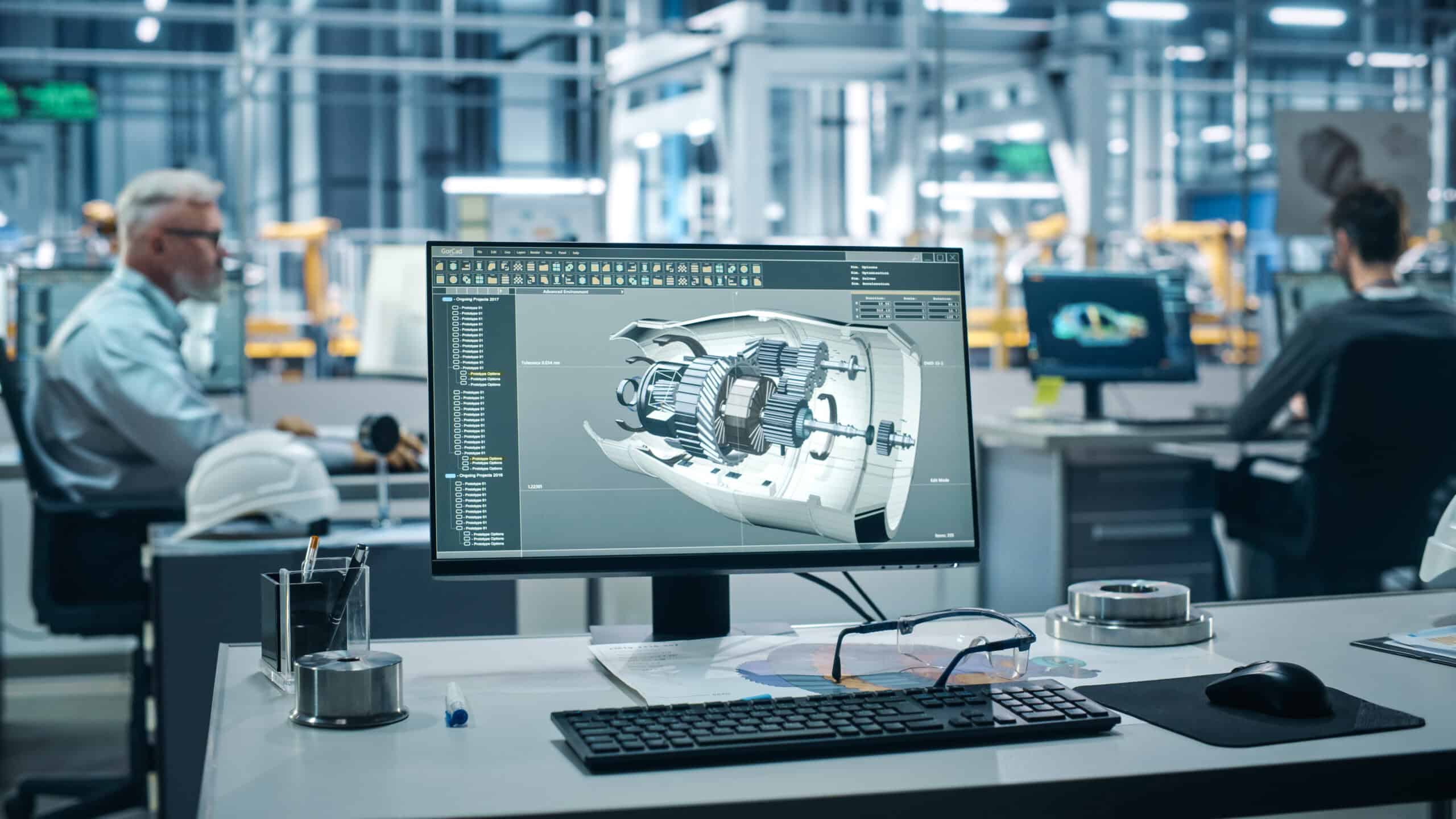 3D-Modell Sicht auf ein Großrambüro. Im Vordergrund ist ein Schreibtisch mit Computerbildschirm. Hierauf ist ein technisches 3D-Modell zu sehen. Im Hintergrund sitzen zwei Männer an Schreibtischen.
