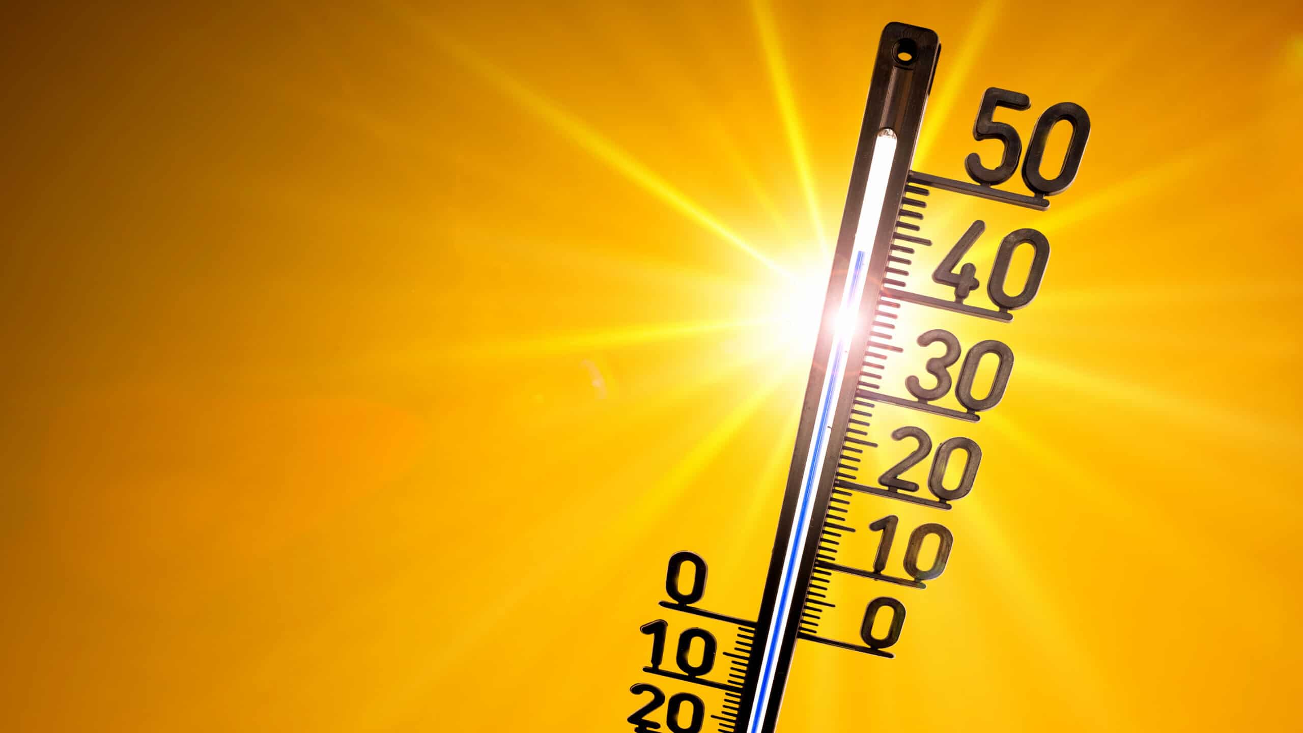Hot summer or heat wave background, glowing sun on orange sky with thermometer Ein Thermometer mit hoher Temperatur ist in der Sonne zu sehen.